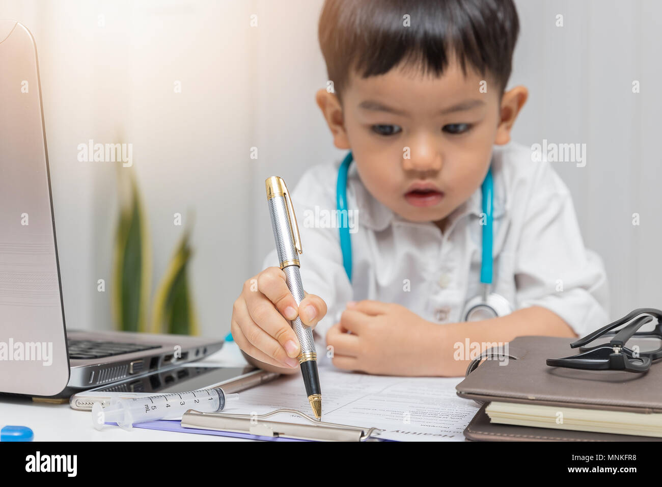 Young asian boy playing doctor and writing on diagnostic chart. Stock Photo