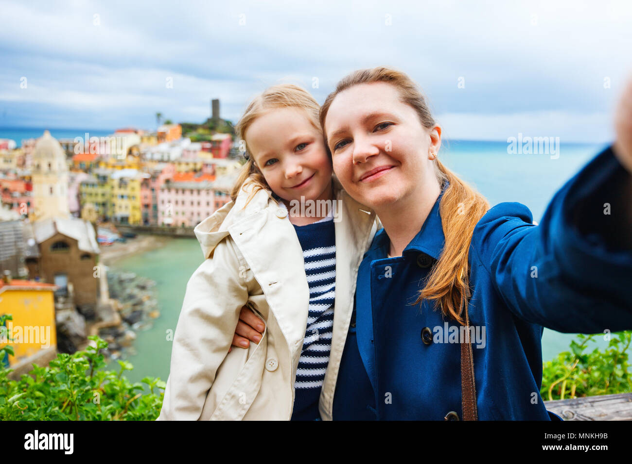 Mother and daughter taking selfie with smartphone having scenic view of colorful village Vernazza, Cinque Terre, Italy on background Stock Photo