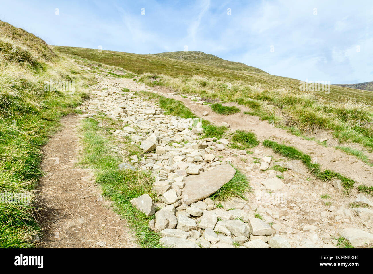 A dry rough stony footpath going up hill towards Grindslow Knoll, Kinder Scout during Summer. Derbyshire, Peak District, England, UK Stock Photo