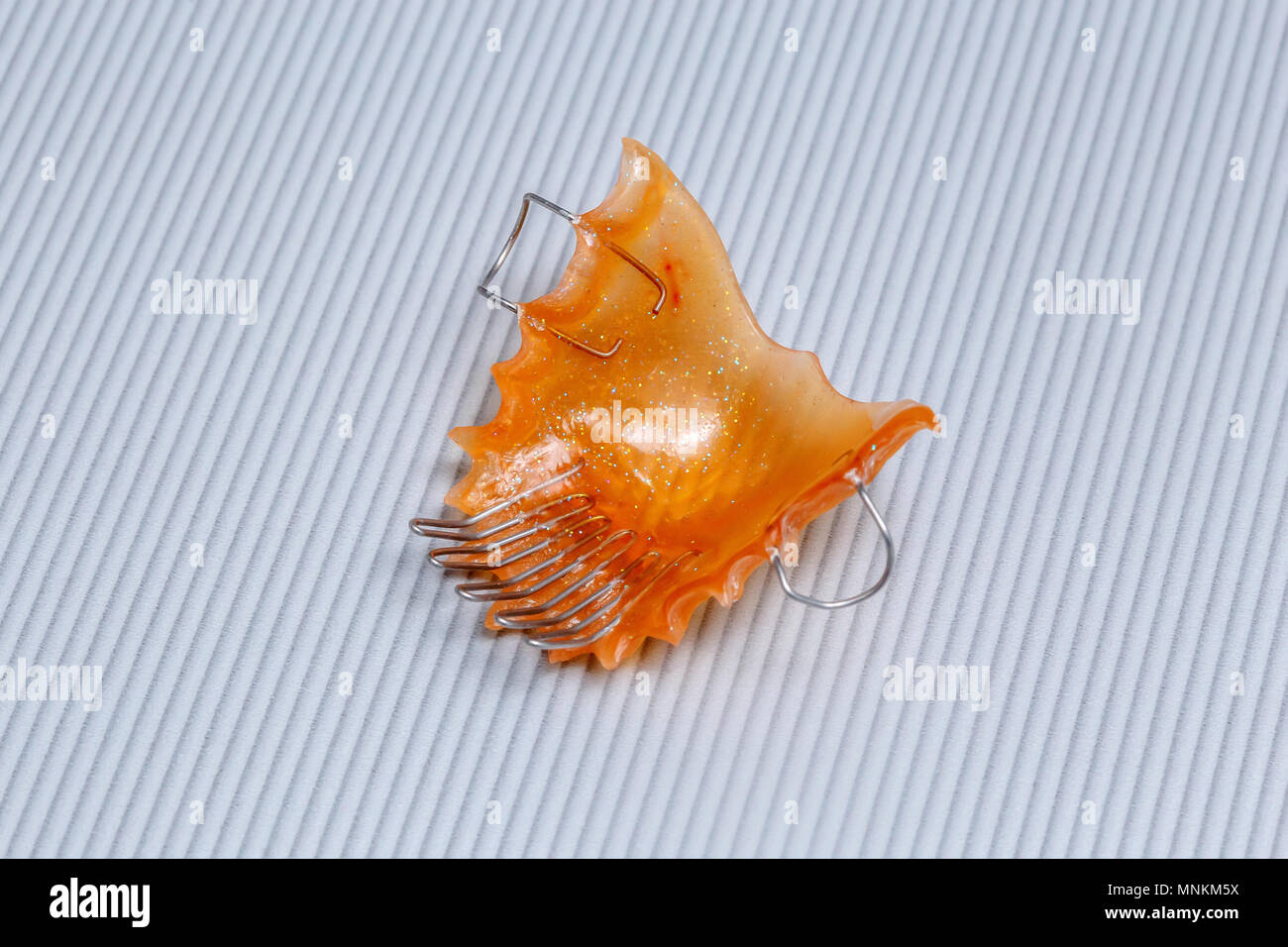 Orange dental braces or retainer for teeth on gray background, closeup ...
