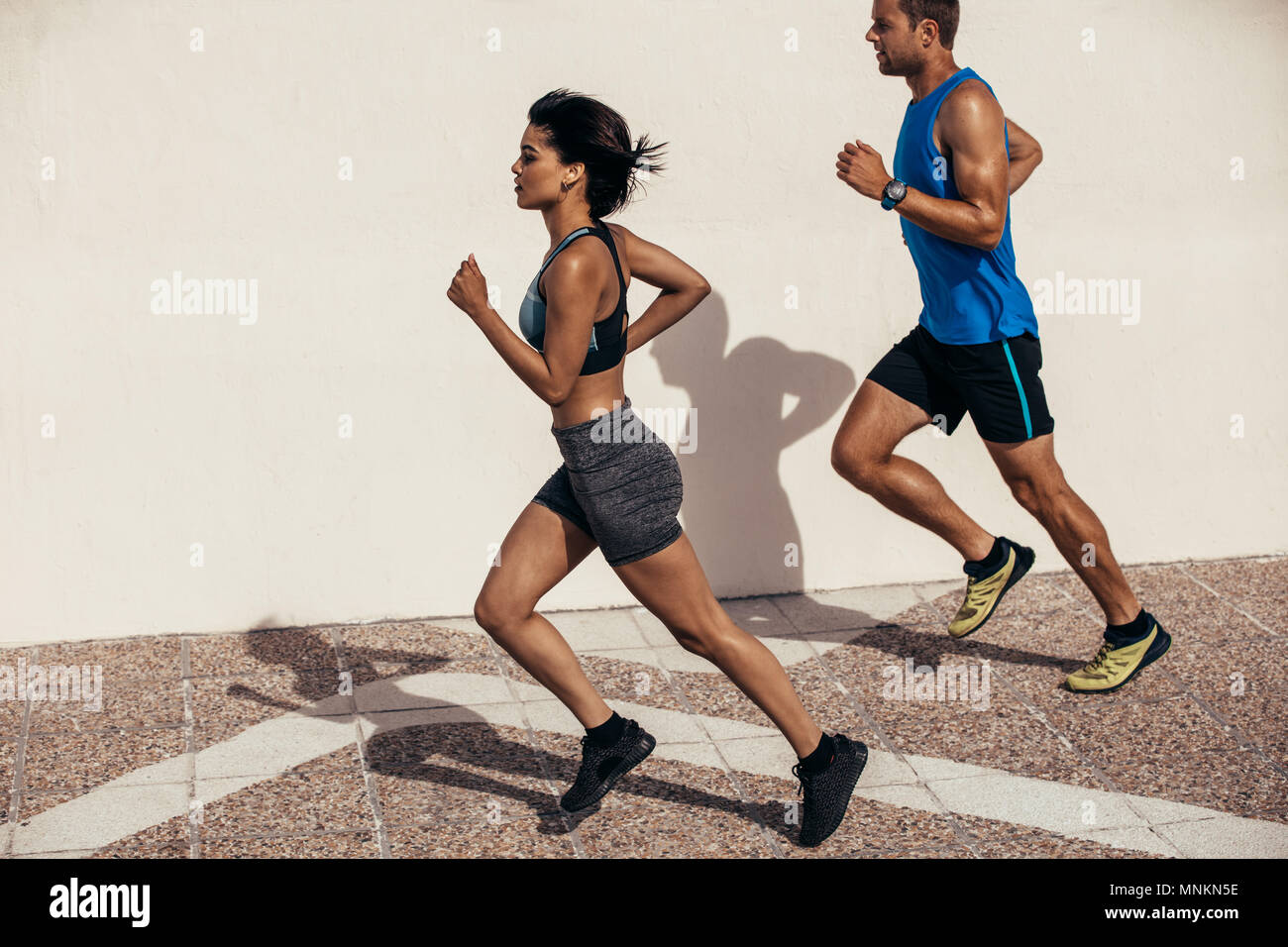 Two runners running outdoors in morning. Man and woman jogging together. Stock Photo
