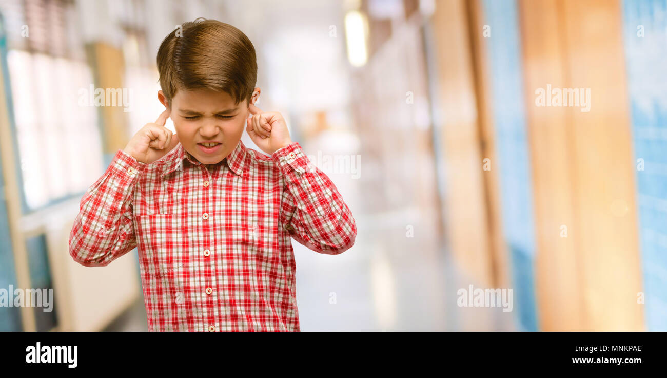 Handsome toddler child with green eyes covering ears ignoring annoying