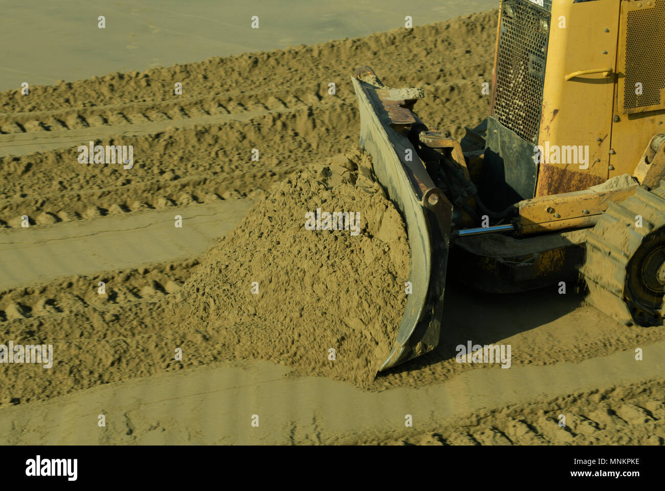 Close-up, detail, scraper of yellow bulldozer pushing wet sand, construction project, blur, copy space Stock Photo