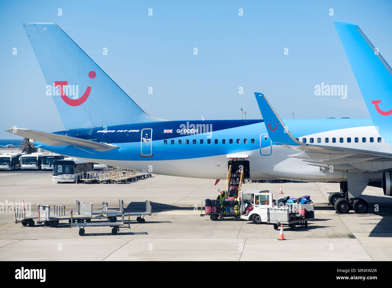 TUI Boeing aircraft on the apron of a busy airport . GSE are servicing a plane. The planes clearly display the TUI logo and on the planes tail Stock Photo