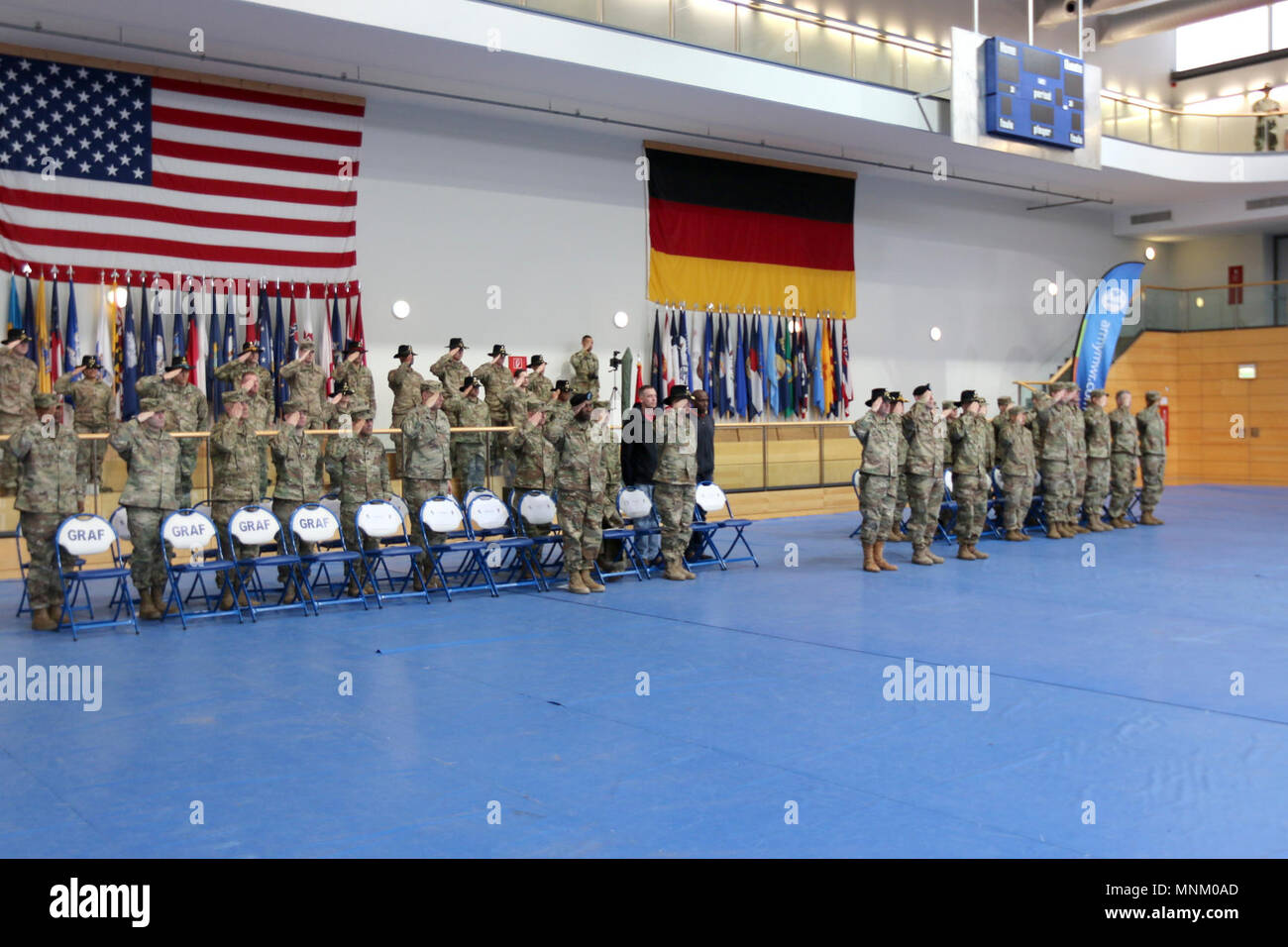 Soldiers from the 5th Squadron, 4th Cavalry Regiment, 2nd Armored Brigade Combat Team, 1st Infantry Division, salute for the playing of the U.S. and German national anthems during a change of command ceremony at the Tower Barracks Physical Fitness Center, Grafenwoehr, Germany, March 17, 2018. Lt. Col. James D. Maxwell relinquished command to Lt. Col. William Bowers during the ceremony. Stock Photo