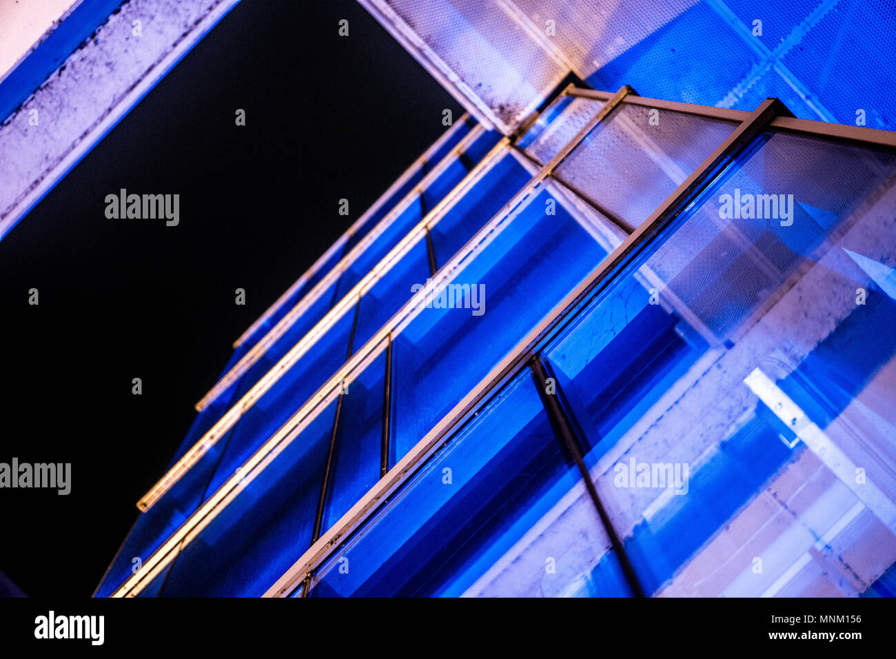 A glass elevator with color changing lights found in the middle of