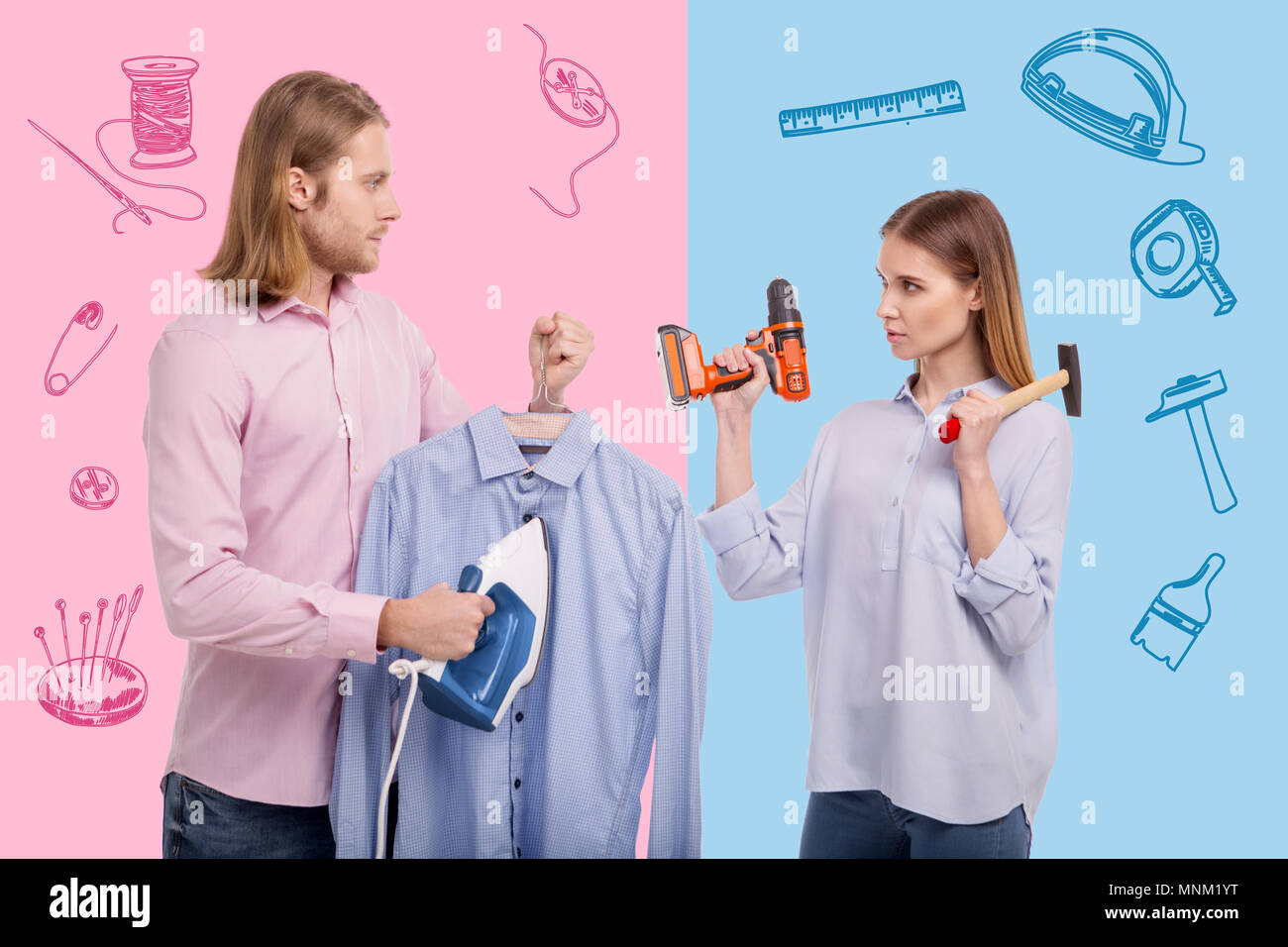 Man with an iron feeling surprised while seeing his wife holding instruments Stock Photo