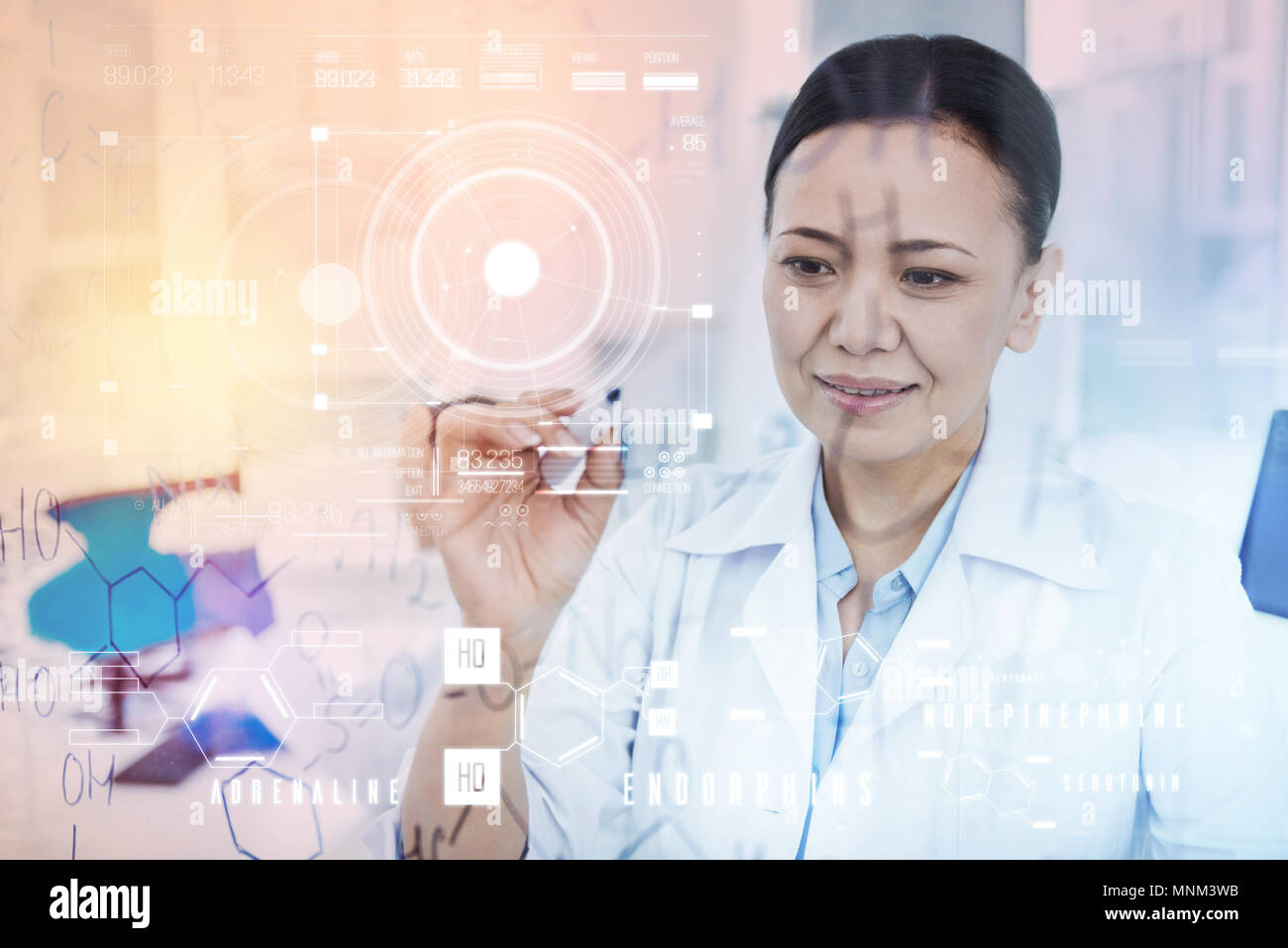 Attentive doctor holding a marker and smiling while writing on the board Stock Photo