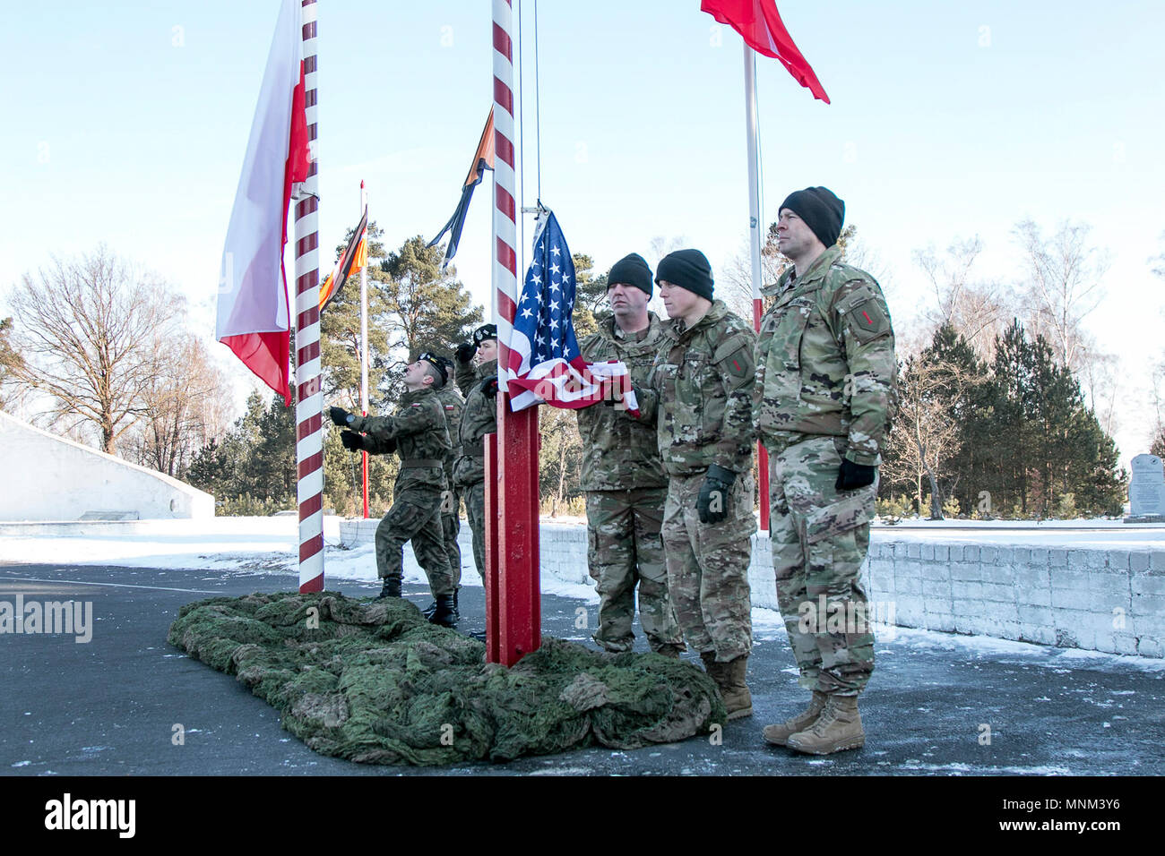 Soldiers of the Polish and U.S. armies take turns hoisting their nation's flags during the playing of their respective national anthems during a welcoming ceremony held in Świętoszów, Poland, for the U.S. 2nd Battalion, 70th Armor Regiment's arrival in Poland, March 19, 2018. Stock Photo