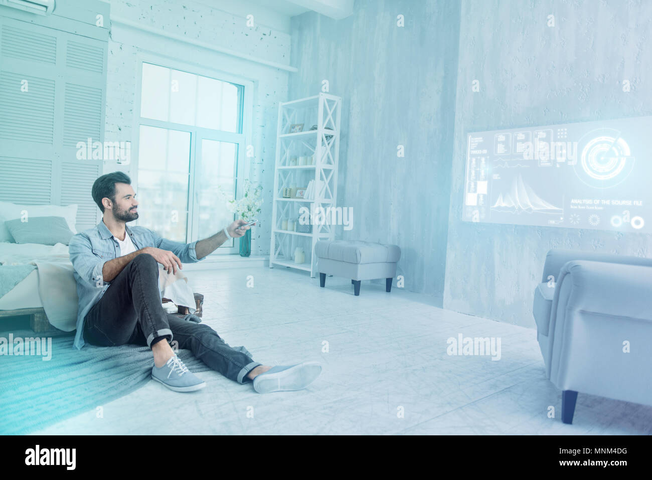 Cheerful designer looking happy while using a remote control at home Stock Photo