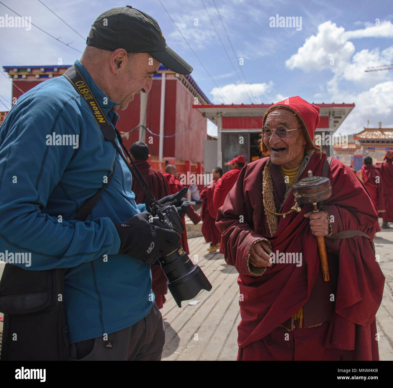 Friendly Tibetan monk talking to a tourist in Yarchen Gar, Sichuan, China Stock Photo