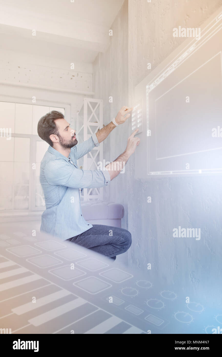 Young man carefully touching a security system while being in smart house Stock Photo