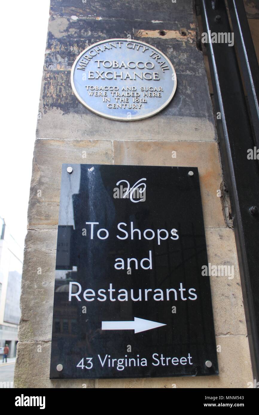 Two signs on Virginia Street, Glasgow: One blue plaque for the Merchant City Trail Tobacco Exchange and one modern sign for shops and restaurants Stock Photo