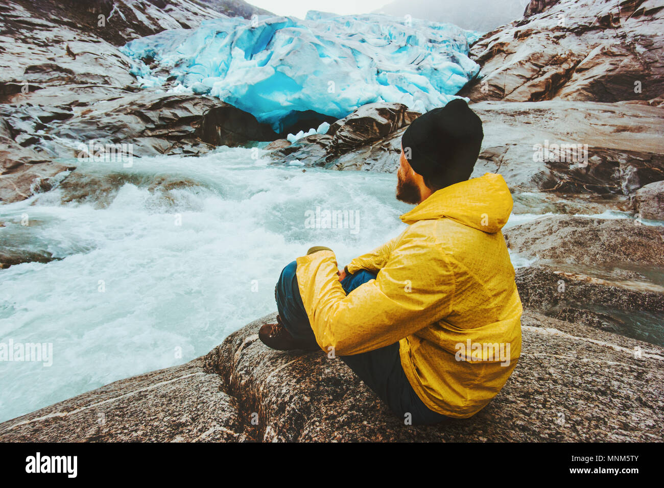 Man traveler relaxing alone travel adventure lifestyle vacations outdoor exploring Norway Nigardsbreen glacier view Stock Photo