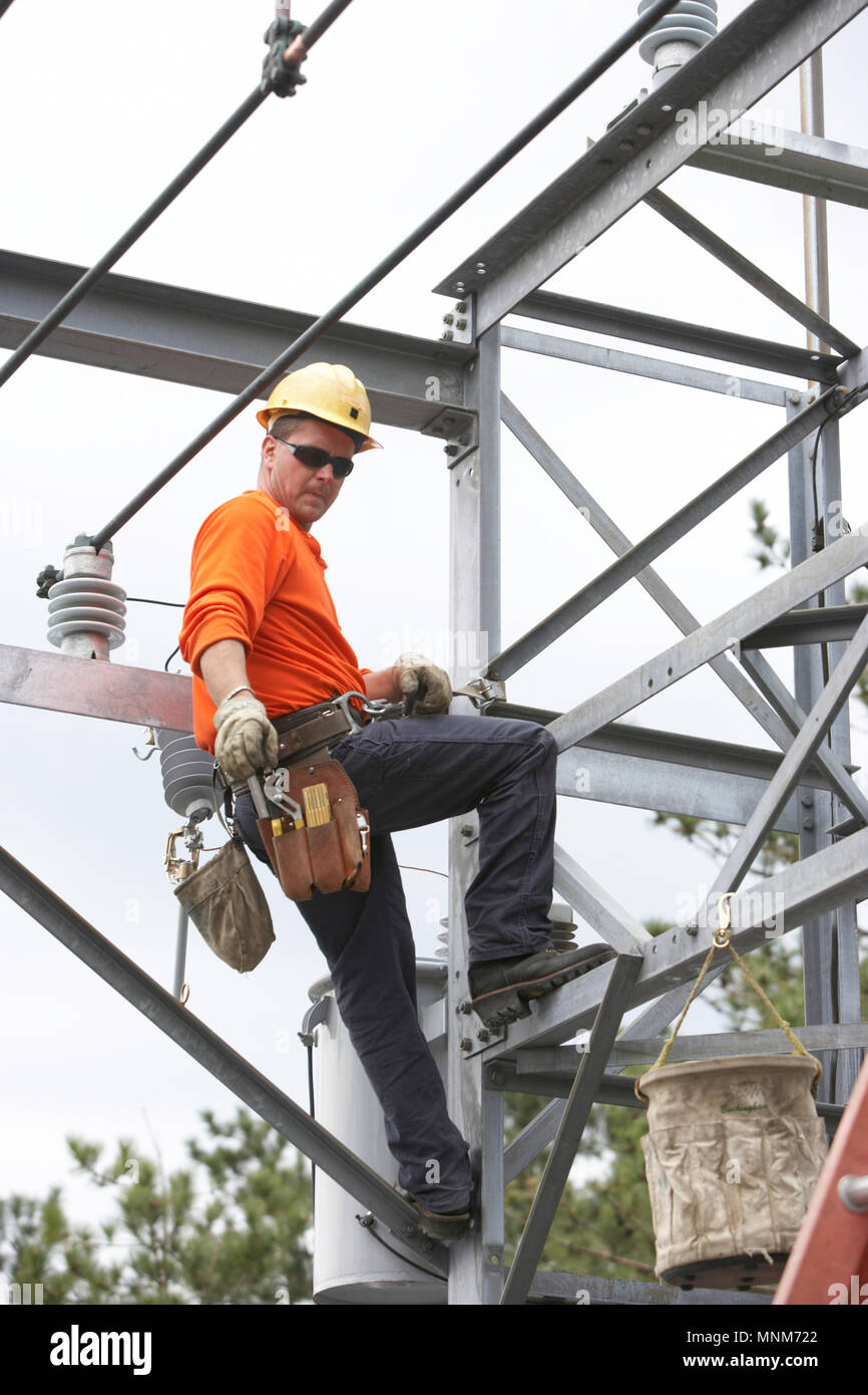 Electric utility blue-collar workman repairing an electric substation ...