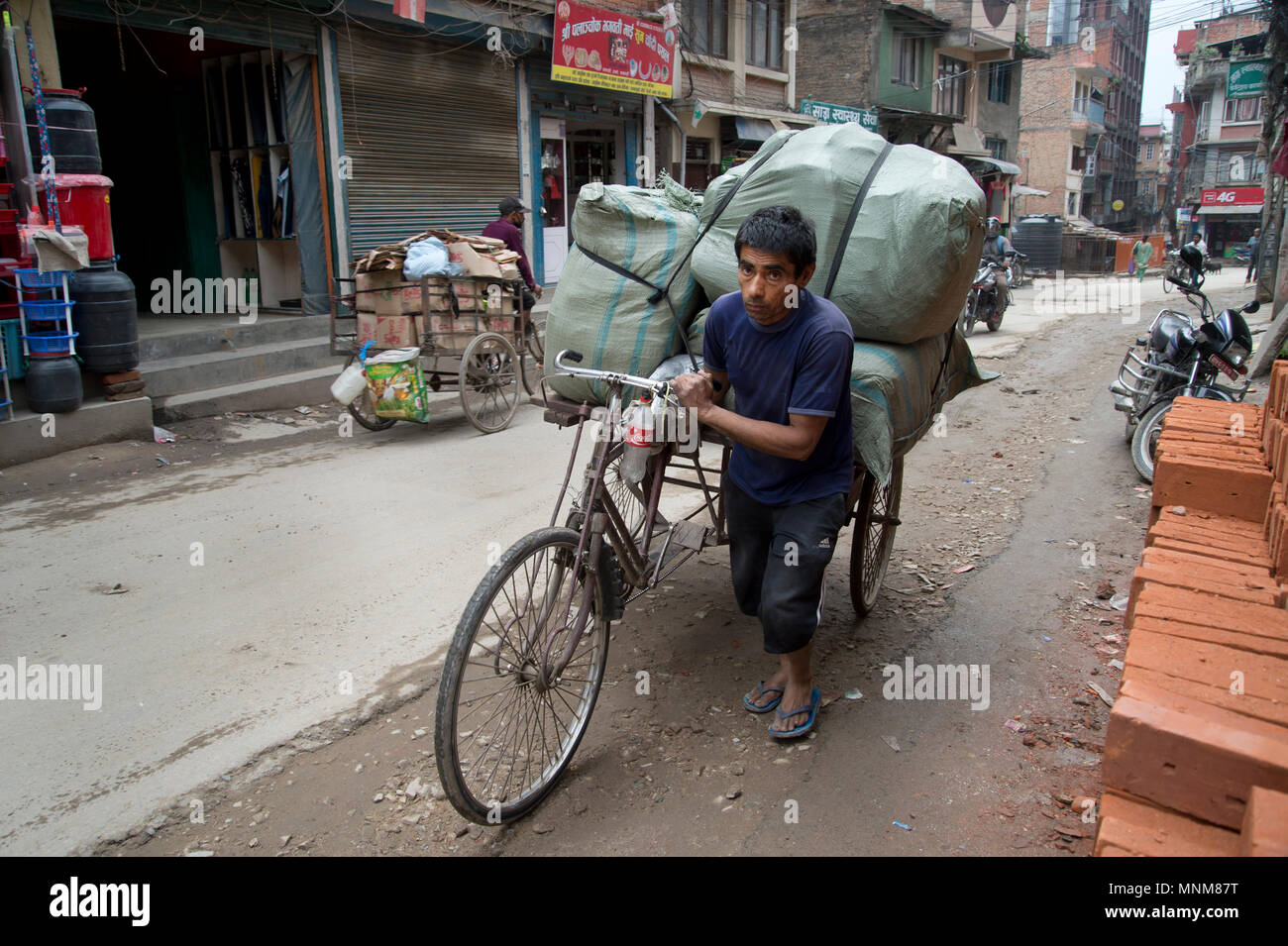 Nepal, Kathmandu. Bicycle transport - a man wheels his heavily laden bike. Stock Photo