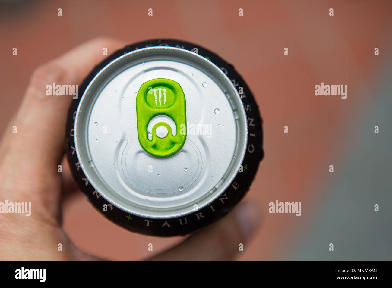 A hand hold a can of Monster Energy drink with a green colour ring pull design Stock Photo