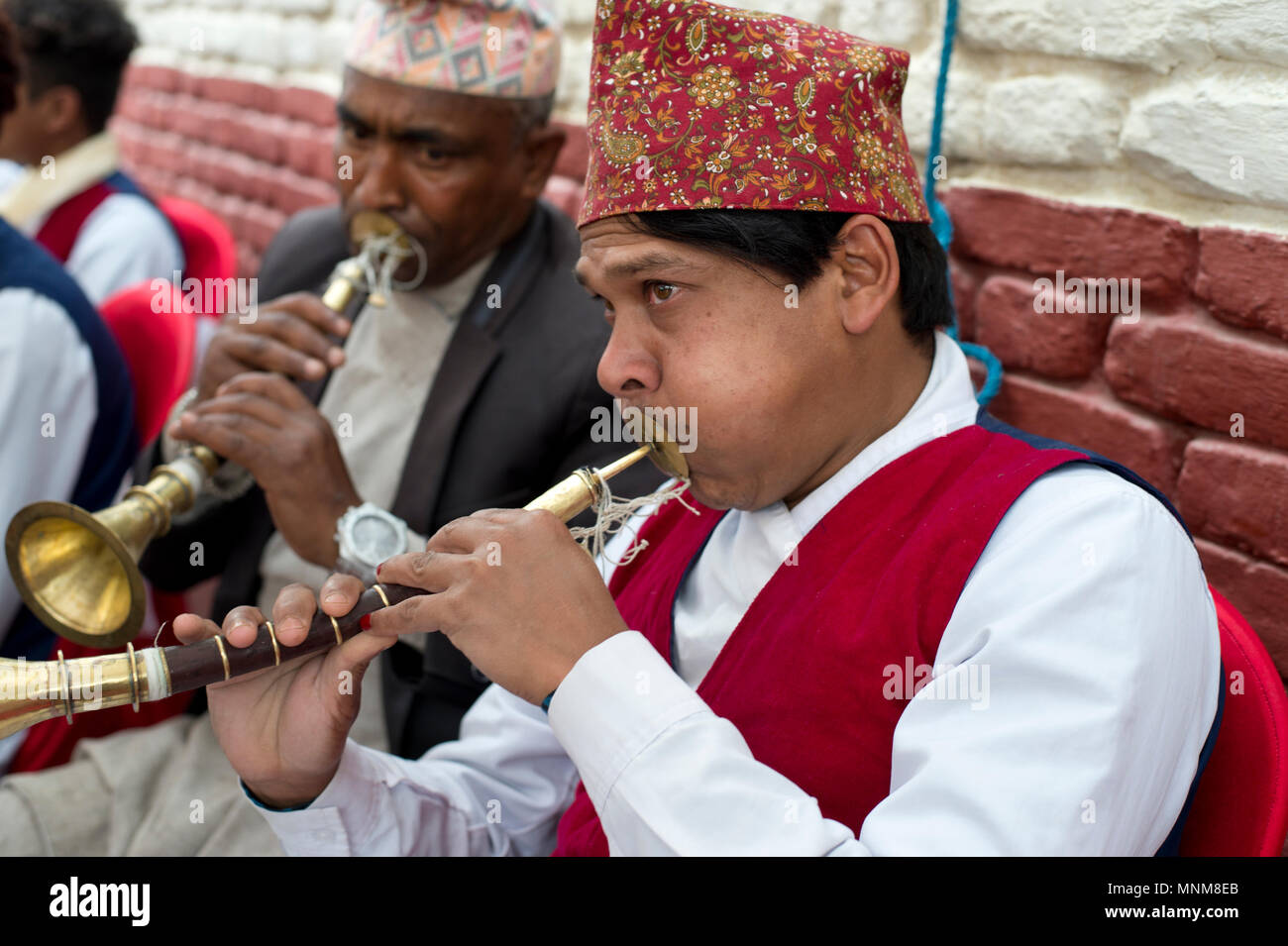 Nepal, Kathmandu. A wedding. Musicians, wearing traditional hats, dhaka topi,  blow on their instruments. Stock Photo