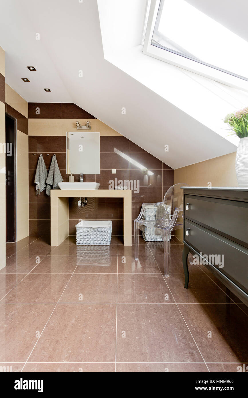 New style attic bathroom with brown tiling, mirror and countertop basin Stock Photo