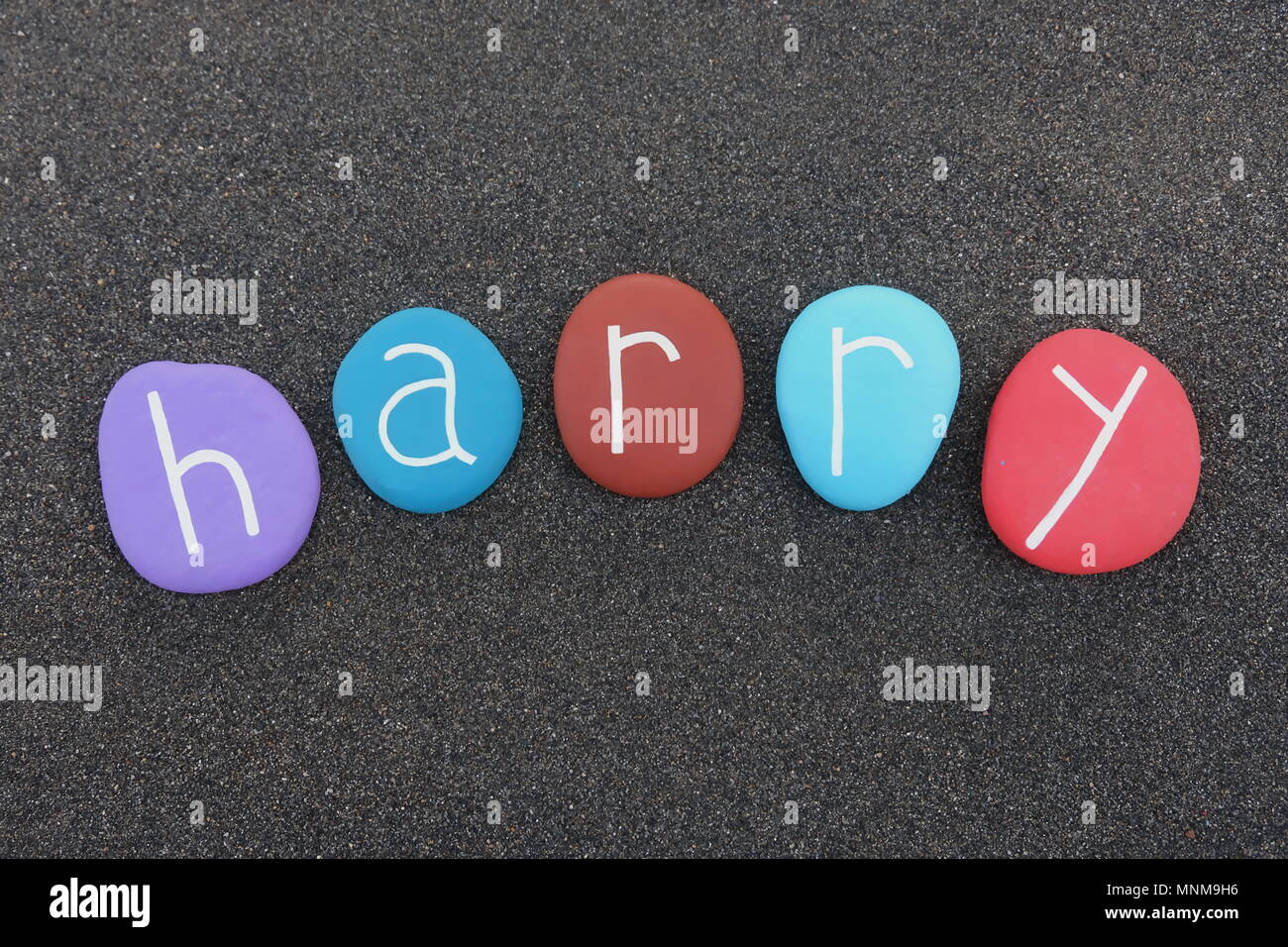 Harry, masculine given name with multicolored stones over black volcanic sand Stock Photo