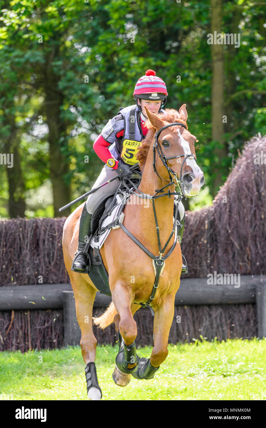Corby, England. 18th May 2018. The horse The Real Rebel Rebel and rider Stephanie Waite gallop onwards after leaping an obstacle fence in the cross country event during the international horse trials at the park of Rockingham Castle, Corby, England on 18 May 2018. Credit: Michael Foley/Alamy Live News Stock Photo