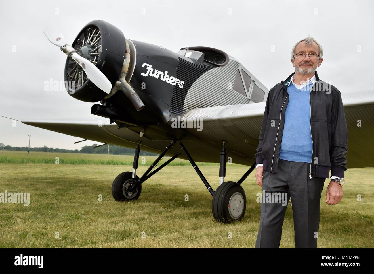 18 May 2018, Germany, Dessau-Rosslau: Bernd Junkers, grandson of Prof. Hugo Junkers, standing beside a replica of a Junkers F 13 which has landed at the airfield during the 13th Hugo Junkers Festival. The replica of one of Prof. Hugo Junkers' most famous creations is the only airworthy example of its kind. It was faithfully built over more than 10 years using original construction plans and laser measurements of museum planes. Photo: Frank May/dpa/ZB Stock Photo