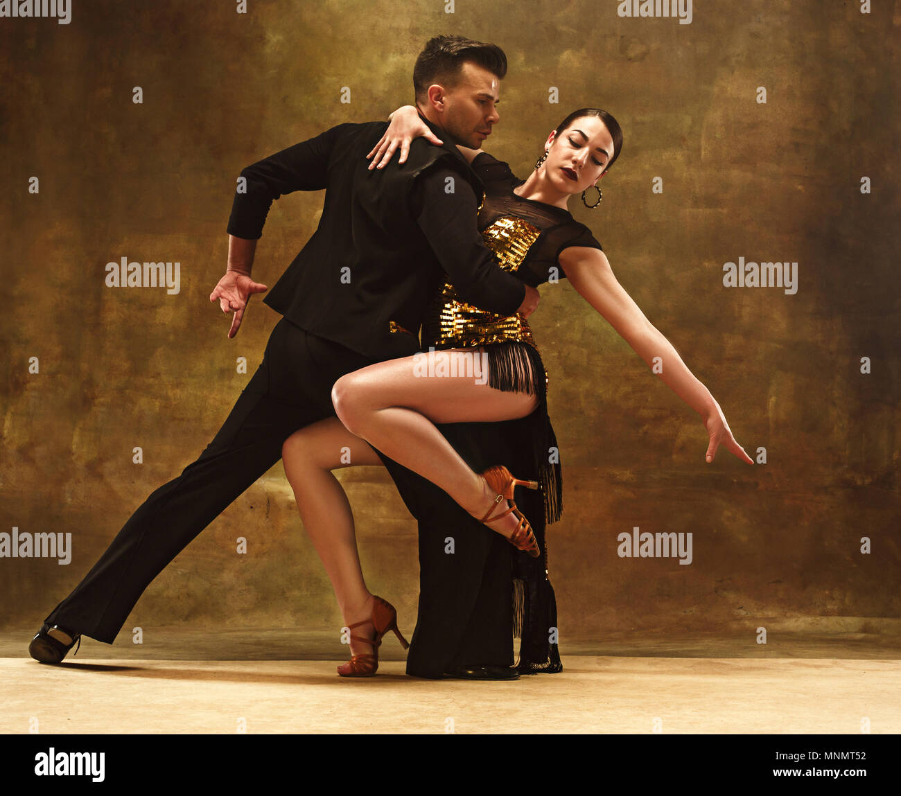 Dance ballroom couple in gold dress dancing on studio background. Stock Photo