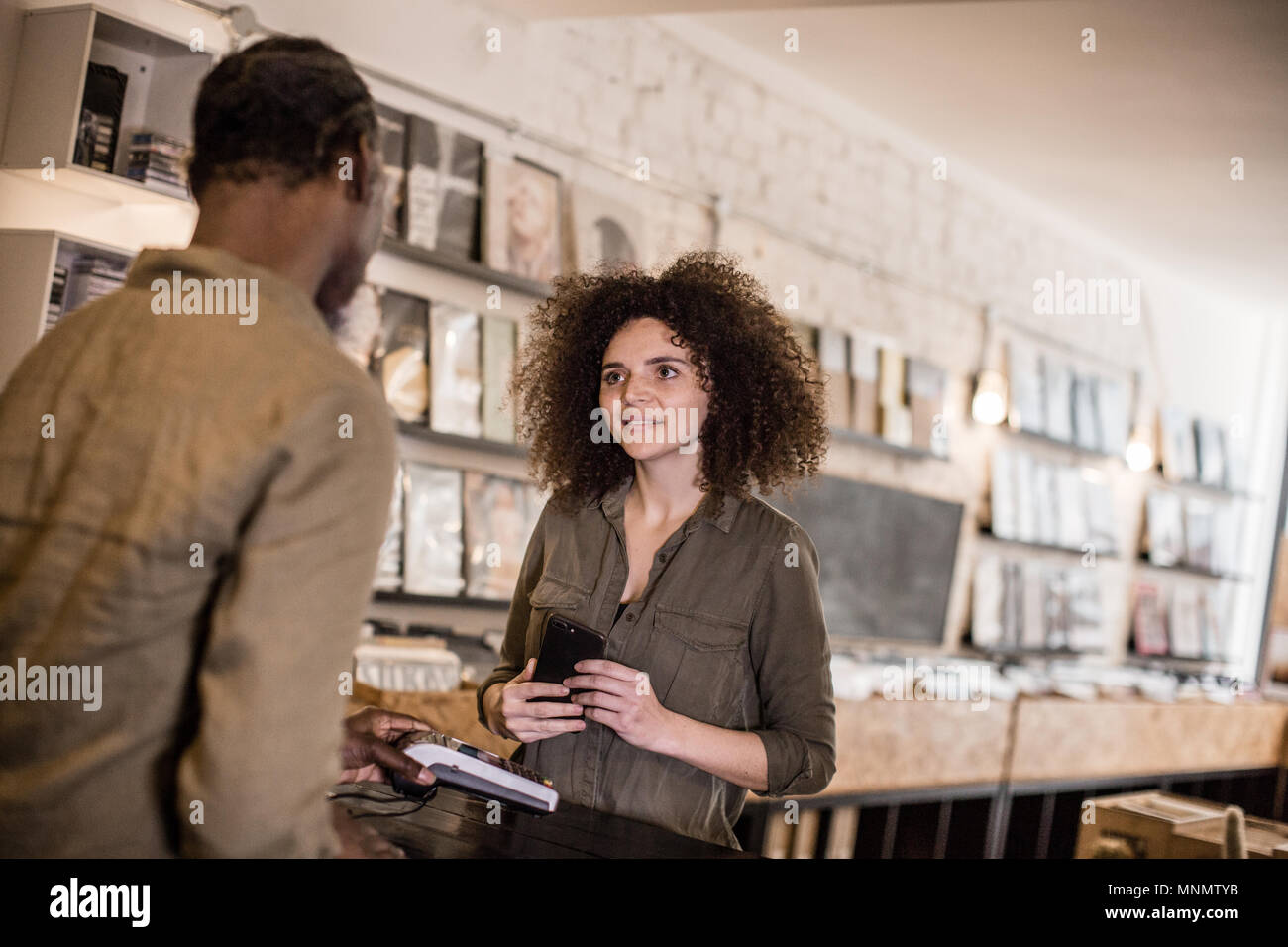 Customer making payment with smartphone in a record store Stock Photo