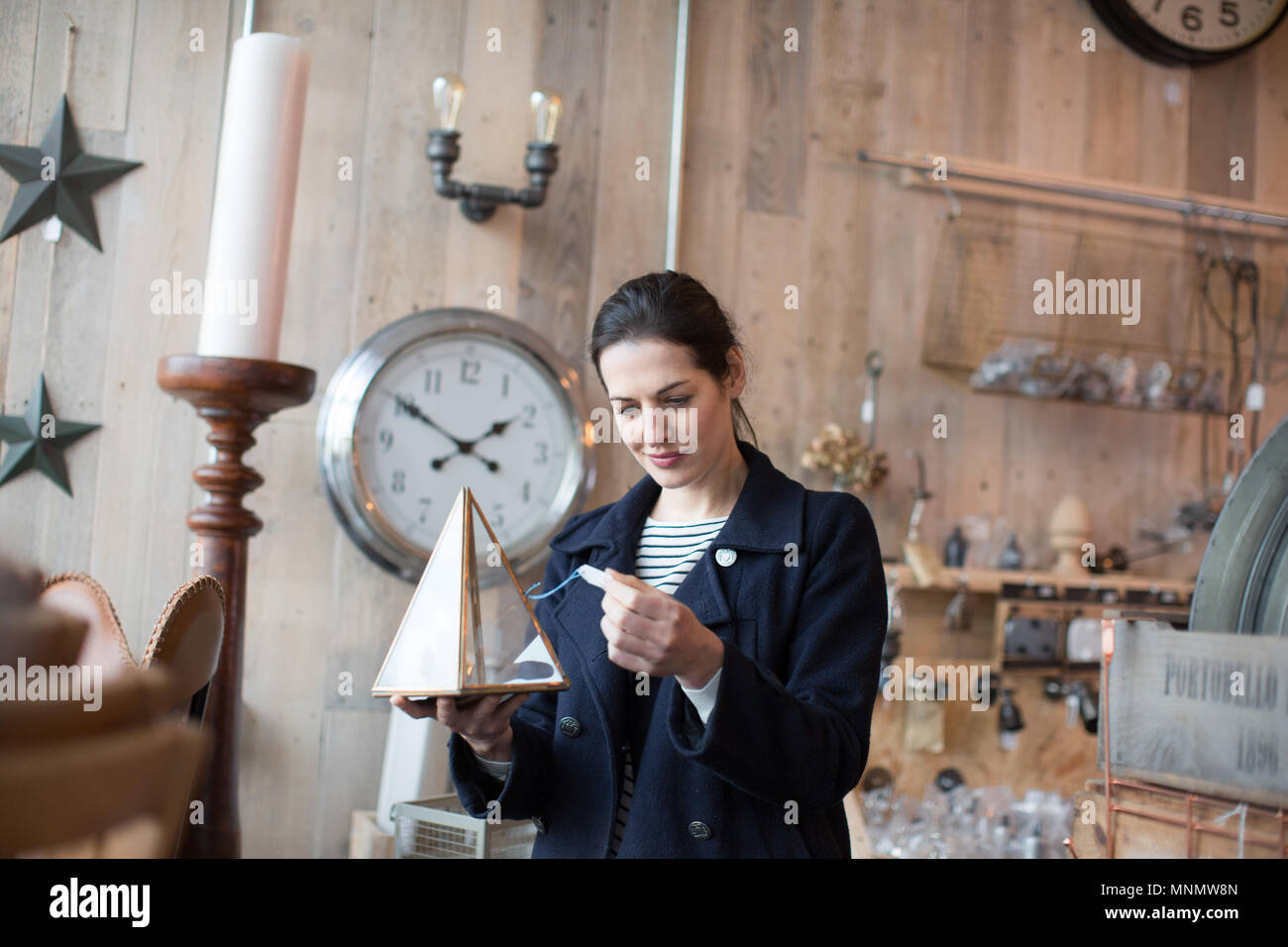 Adult female looking at price tags in a vintage antique store Stock Photo