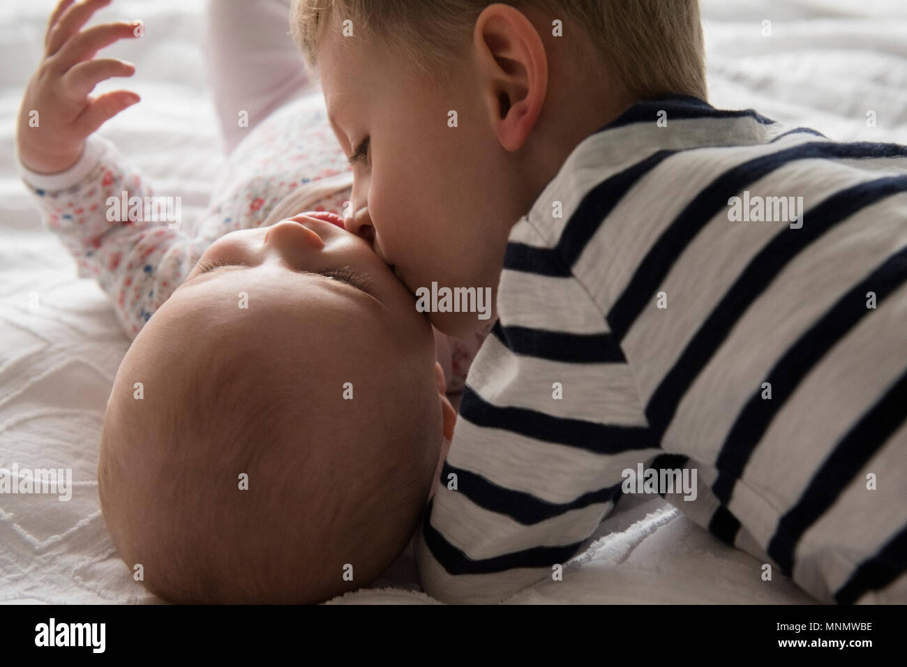 Brother kissing little sister (18-23 months, 4-5) with love Stock Photo