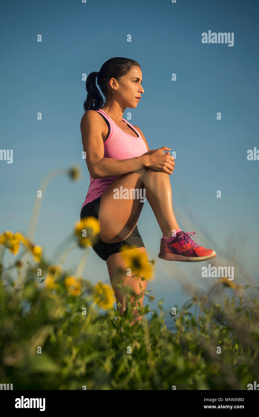 Woman stretching against blue sky Stock Photo