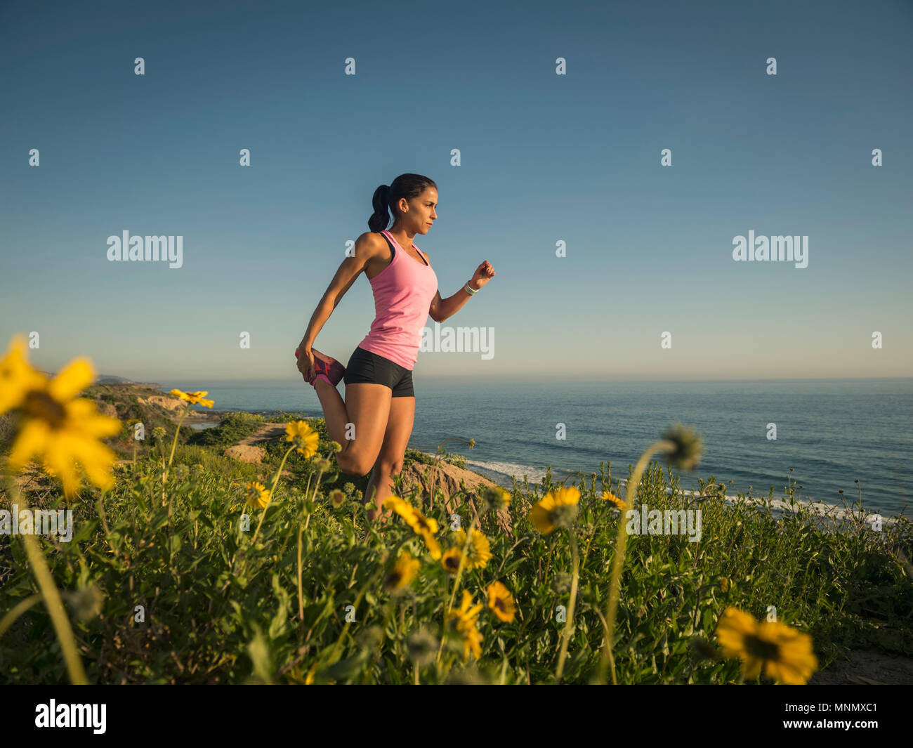 USA, California, Newport Beach, Woman stretching on cliff Stock Photo