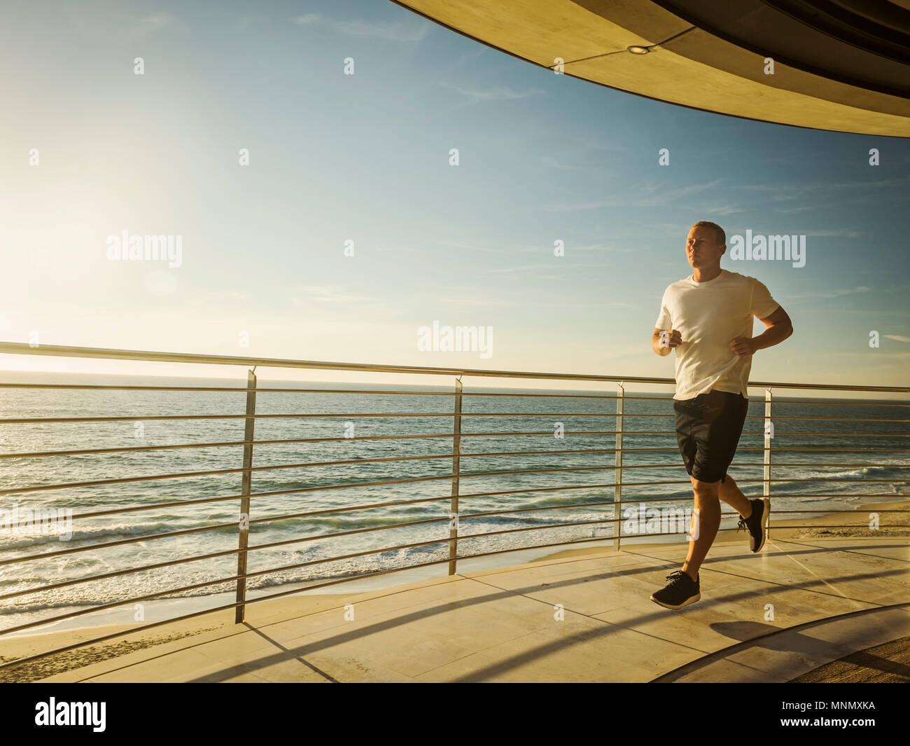 Man jogging by ocean Stock Photo