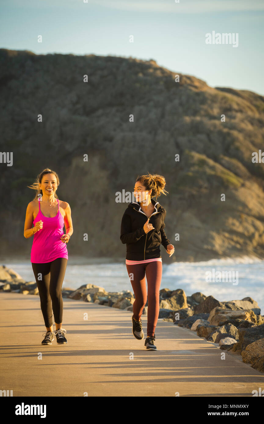 Two women jogging along sea Stock Photo