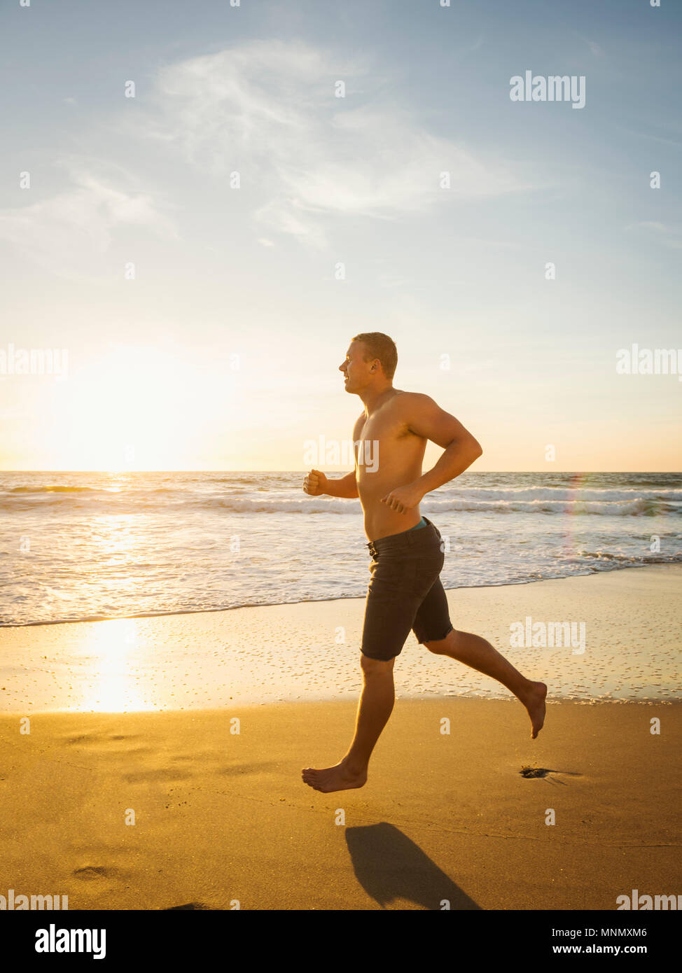 Man jogging along beach Stock Photo