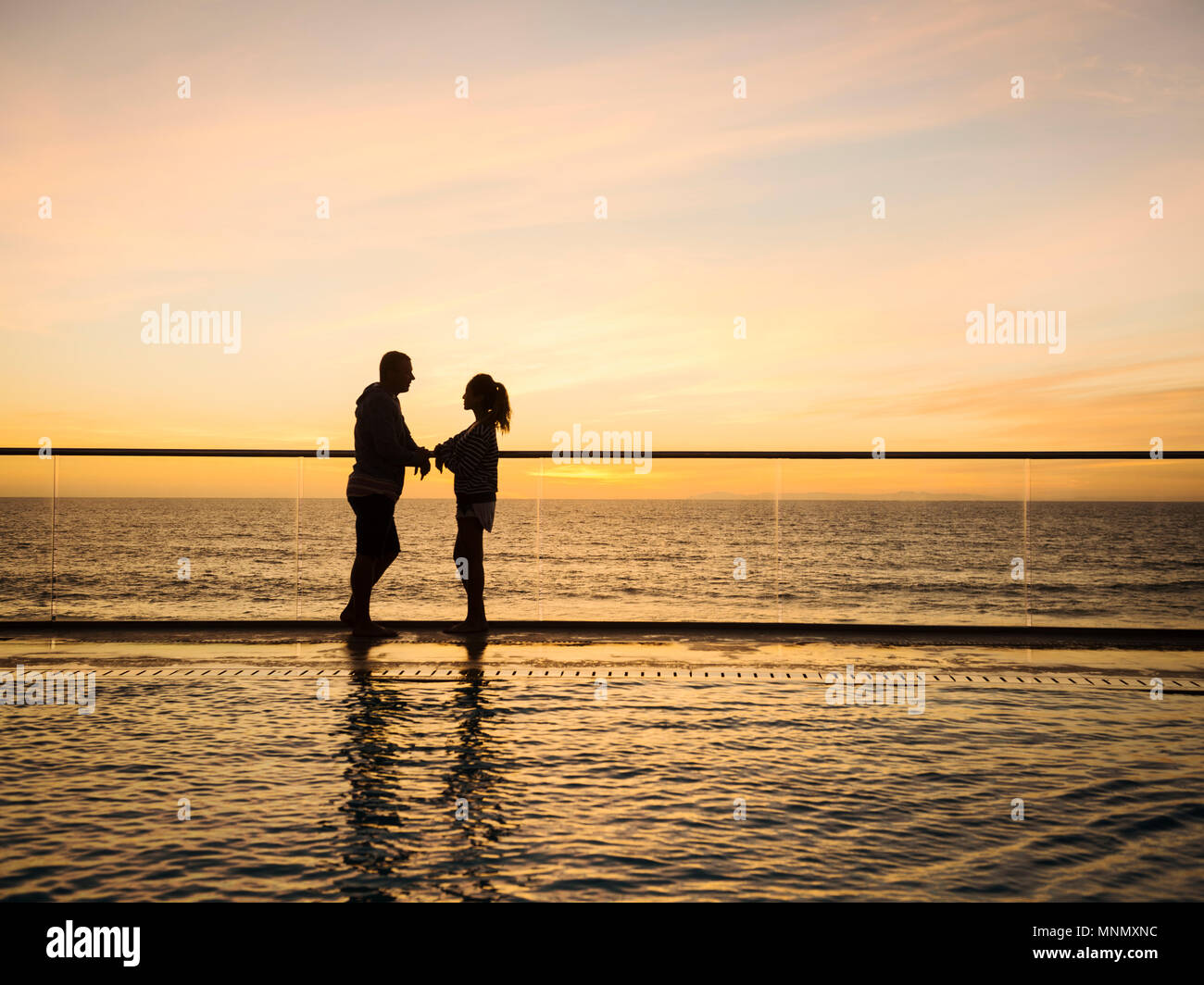 Couple at poolside over sea Stock Photo