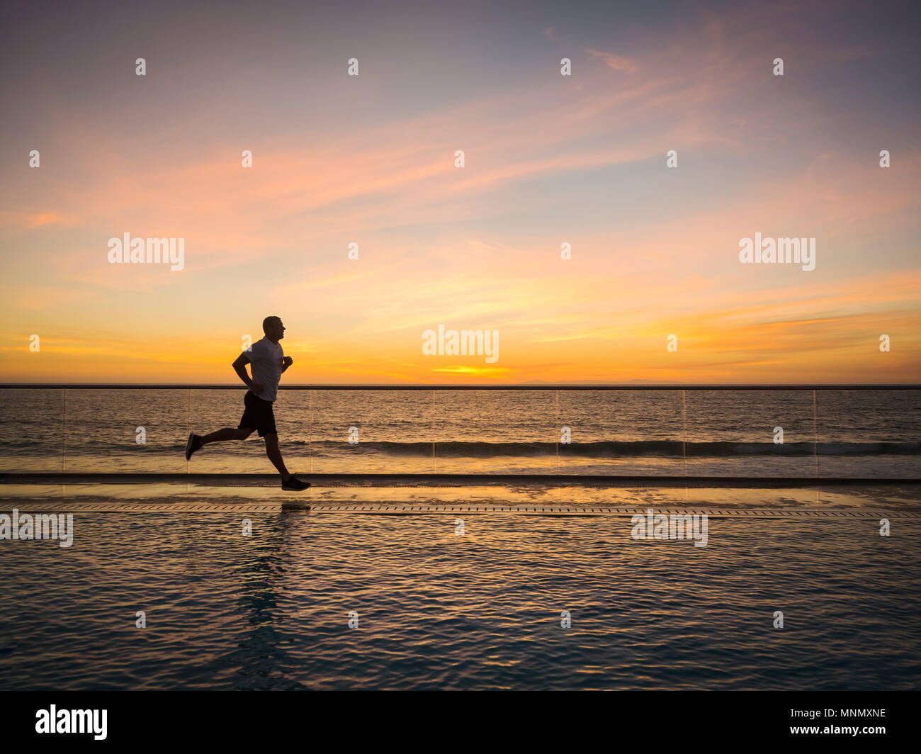 Man jogging along poolside Stock Photo