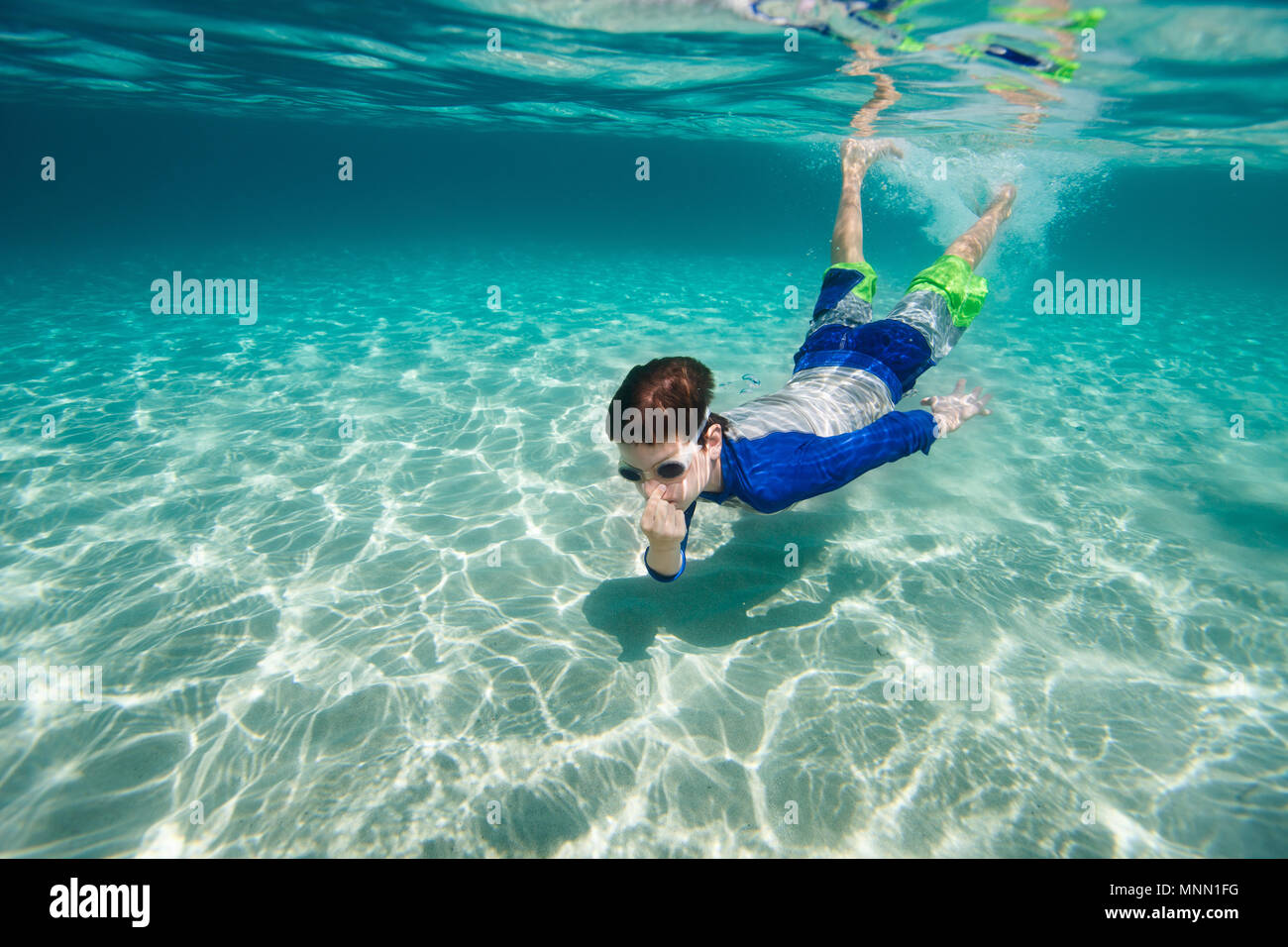 Cute teenage boy swimming underwater in shallow turquoise water at tropical  beach Stock Photo - Alamy