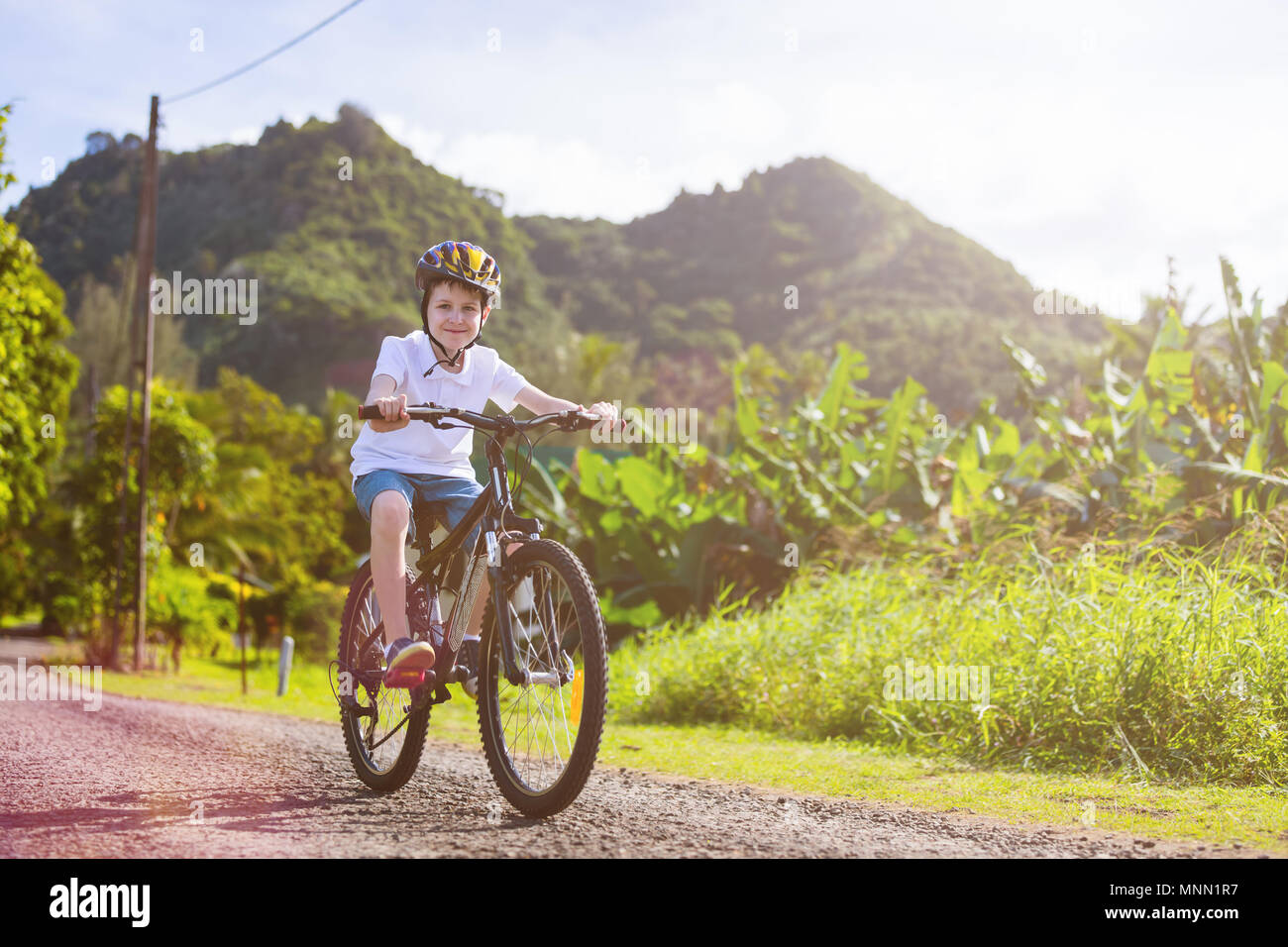 Teenager boy biking at tropical settings having fun Stock Photo