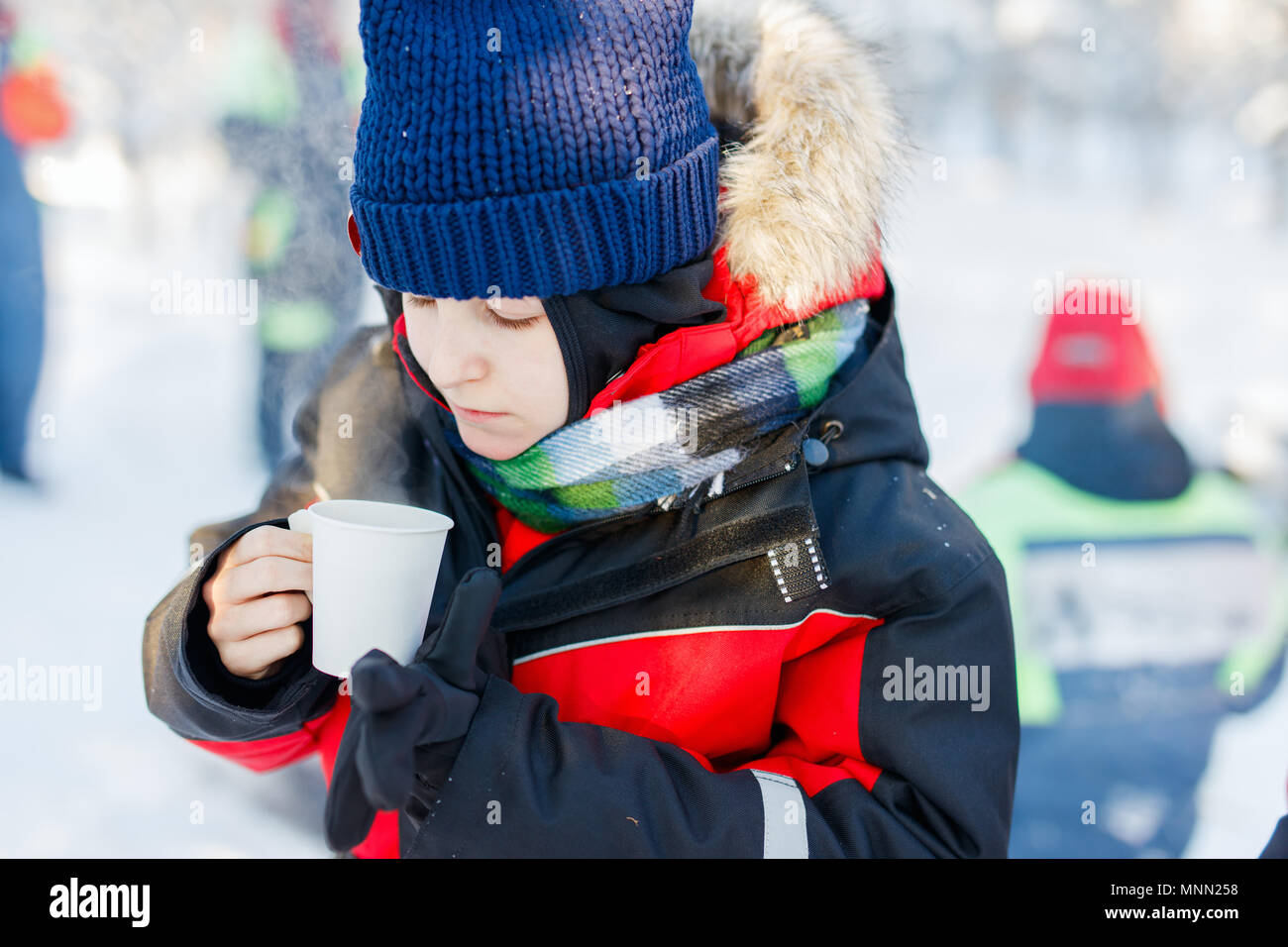 Cute boy outdoors on beautiful winter snowy day drinking hot tea Stock Photo