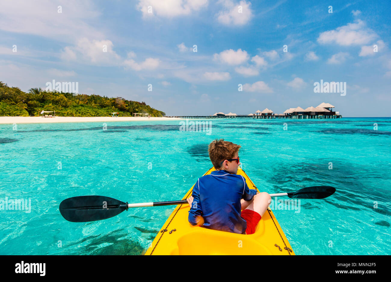 Back view of happy teenage boy on a kayak at tropical lagoon Stock Photo