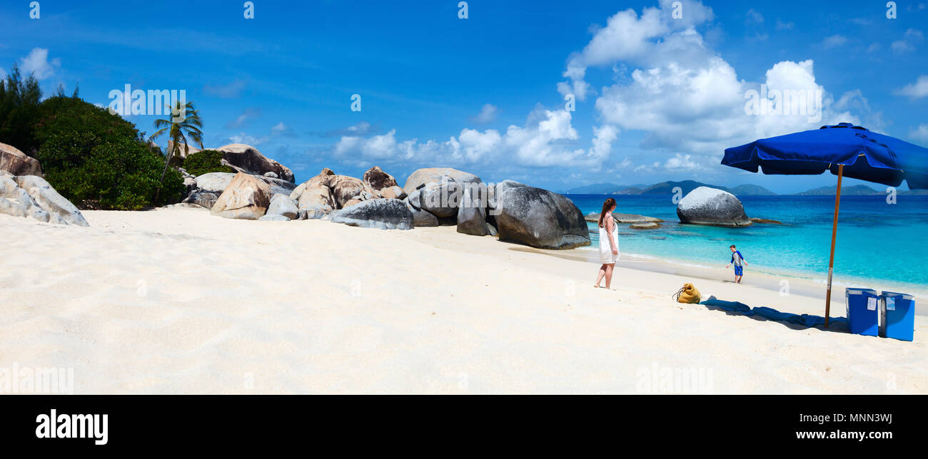Family on picture perfect beach with blue umbrella, white sand, turquoise ocean water and blue sky at tropical island in Caribbean Stock Photo