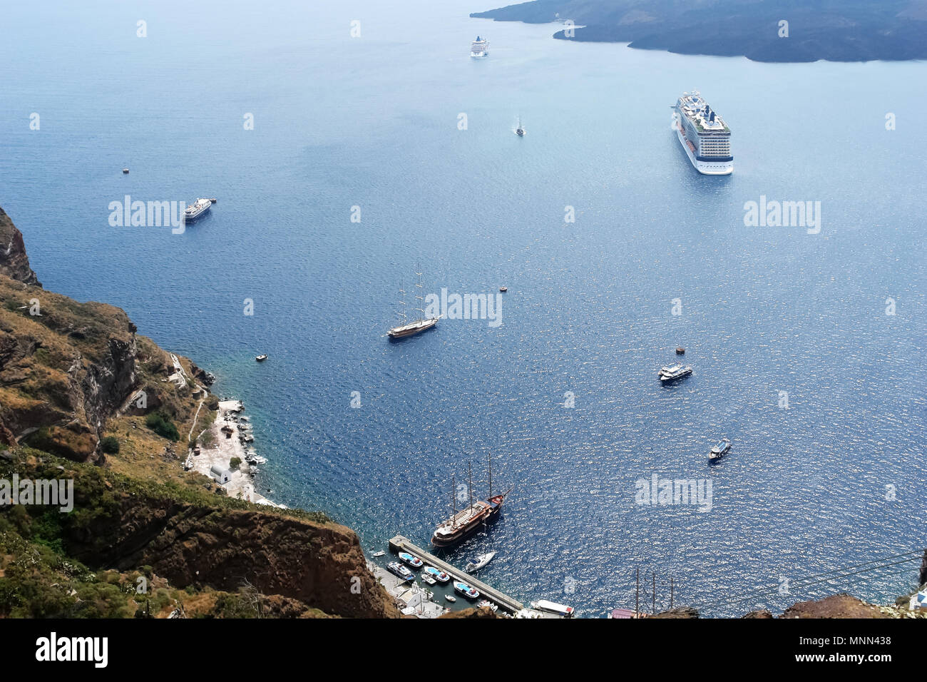 A view from above of the large and small ships in the bay of the volcanic island of Santorini, Greece. Stock Photo