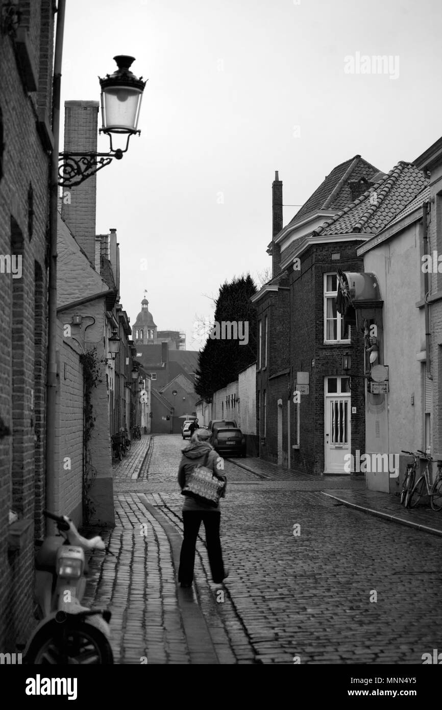 Speelmanstraat, Brugge, Belgium: a quiet winter's street, with wet cobbles and a lone pedestrian Stock Photo