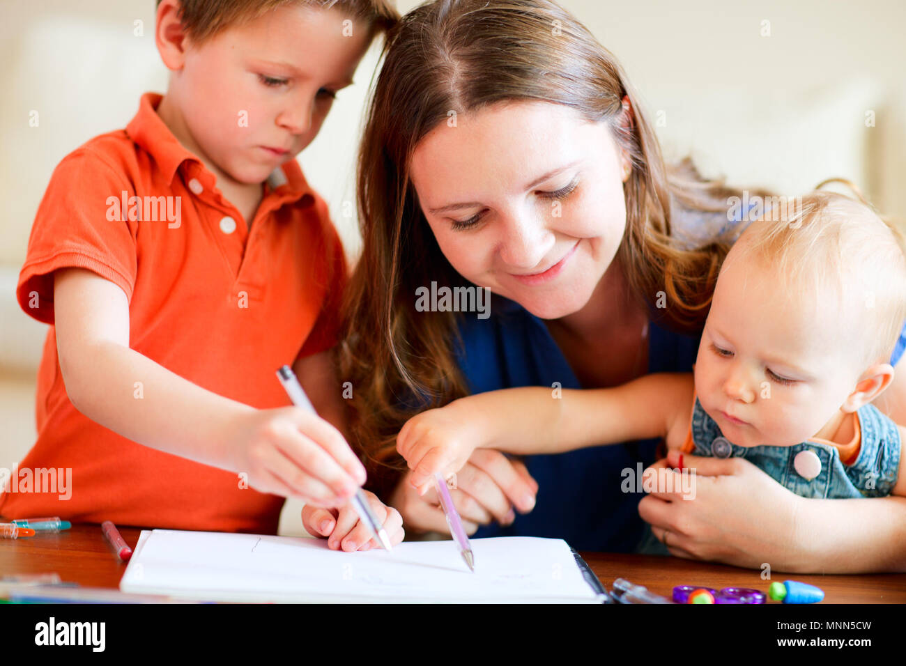 Young mother and her two kids drawing together Stock Photo