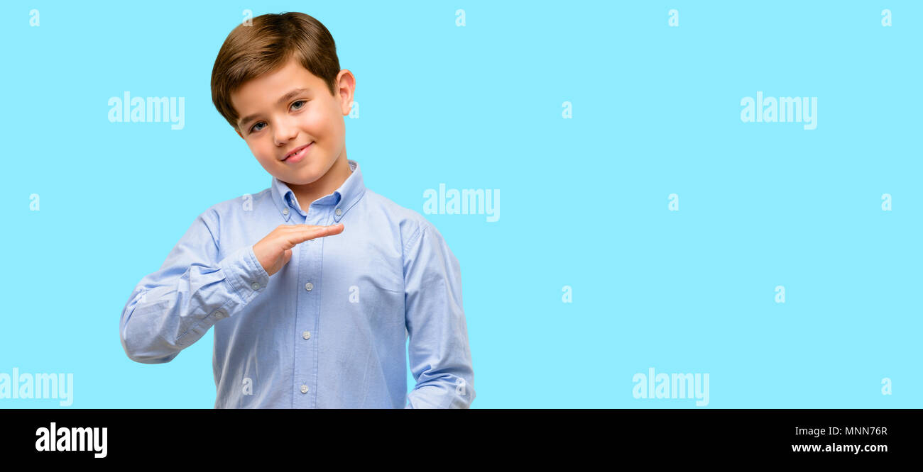 Handsome toddler child with green eyes holding something, size concept over blue background Stock Photo