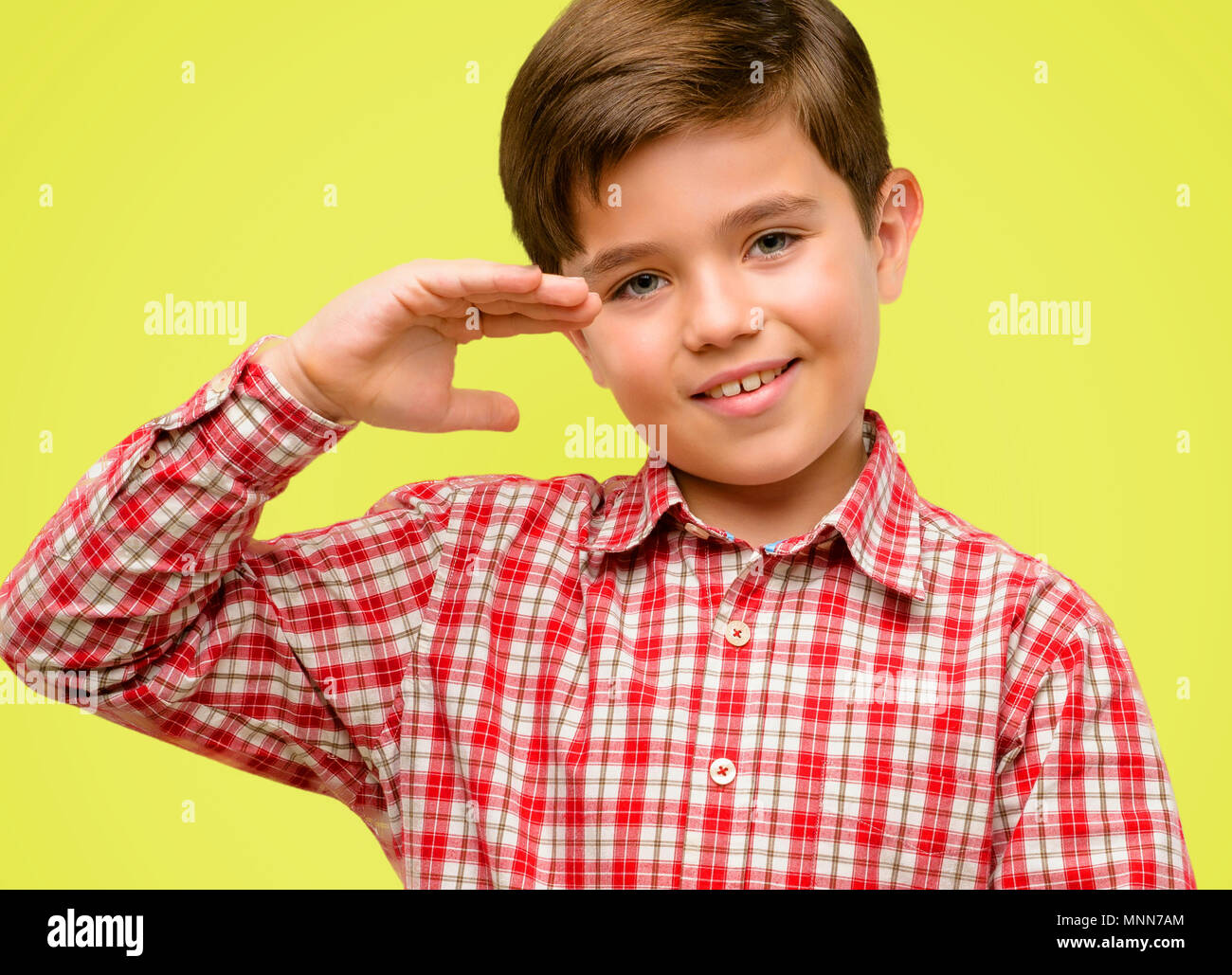 Handsome toddler child with green eyes holding something, size concept over yellow background Stock Photo