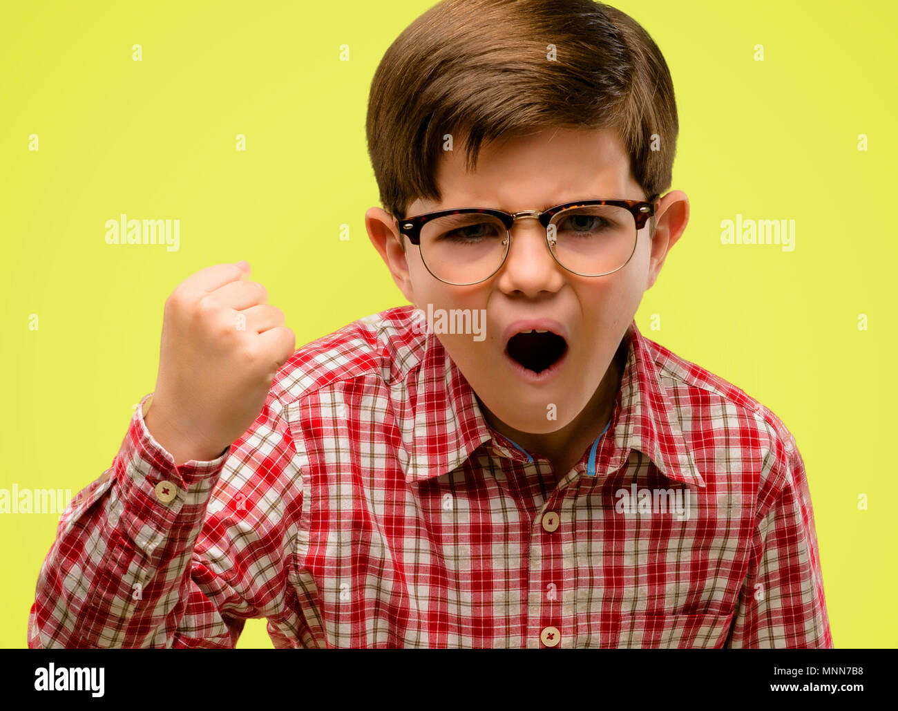Handsome toddler child with green eyes irritated and angry expressing negative emotion, annoyed with someone over yellow background Stock Photo
