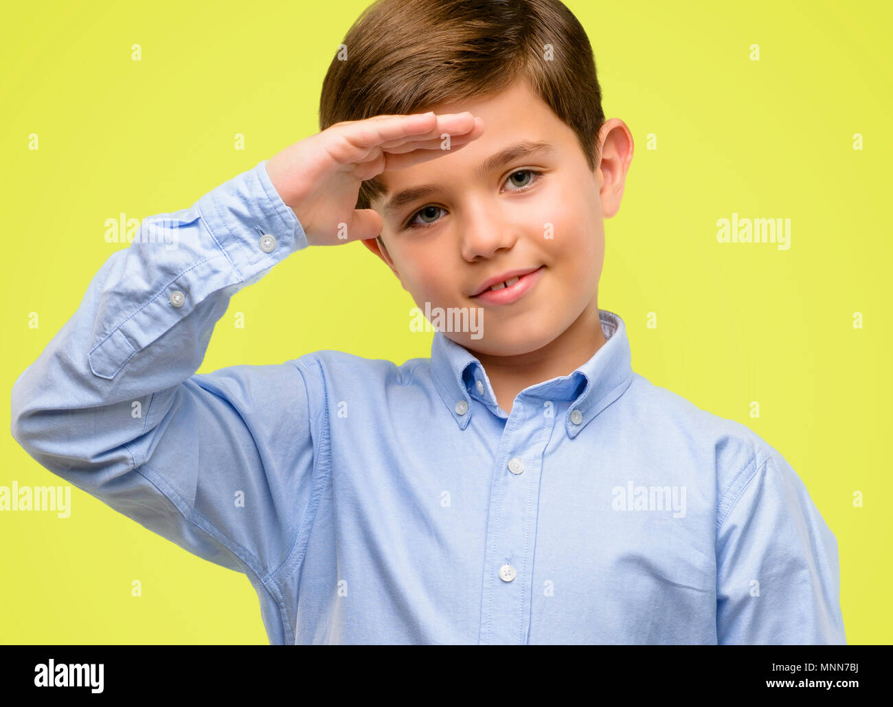 Handsome toddler child with green eyes holding something, size concept over yellow background Stock Photo