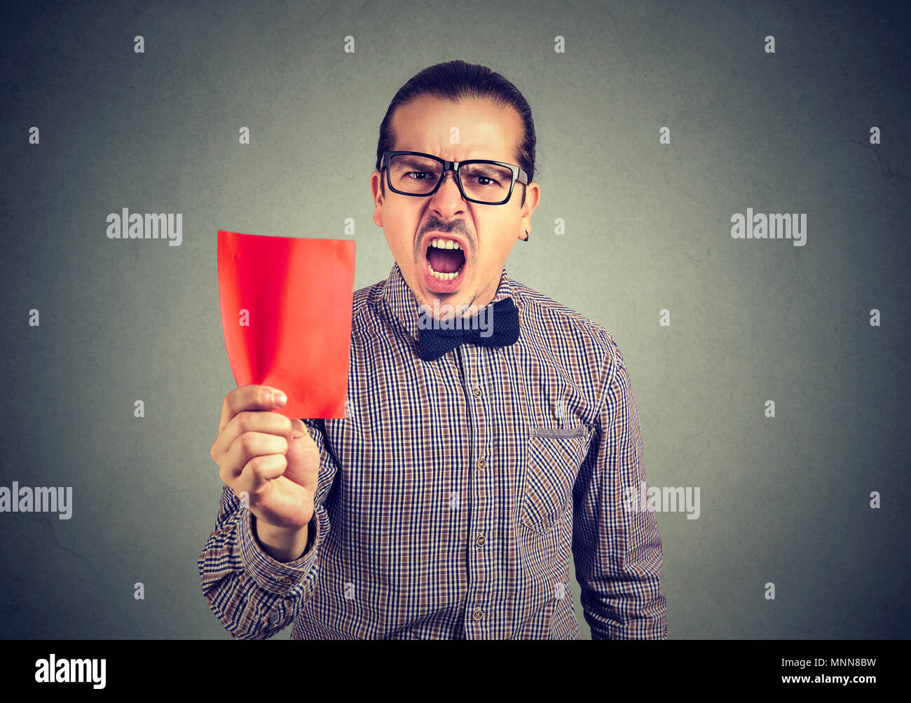 Young frustrated business man manager showing a red card screaming at camera Stock Photo